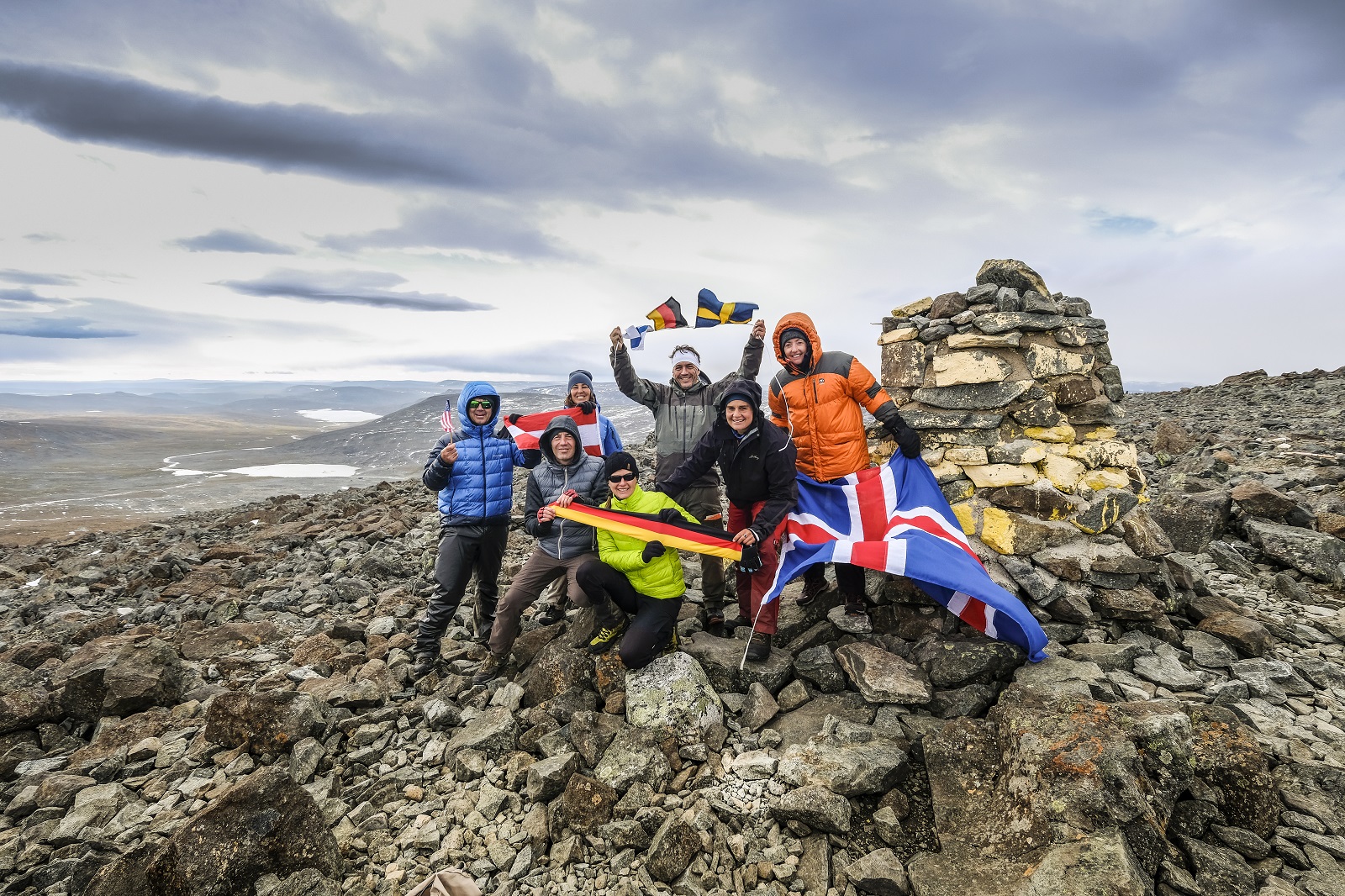 The seven members of the group pose with the flags of their nati