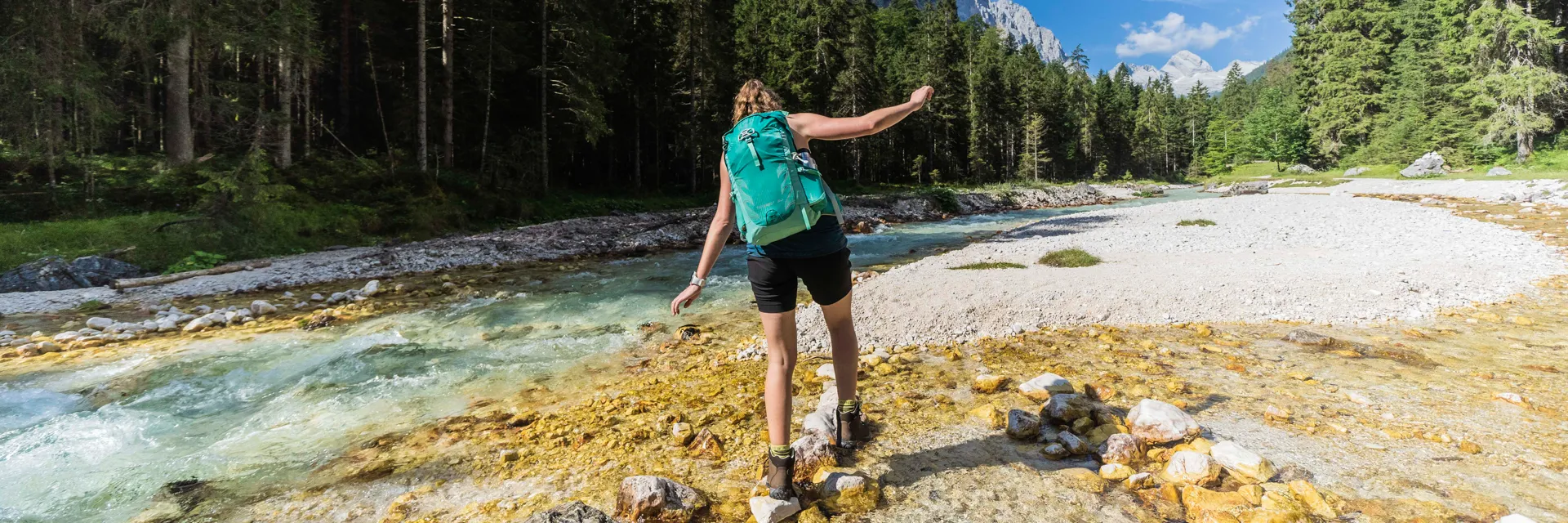 Woman Hiking Through Stream Backpack 1920px