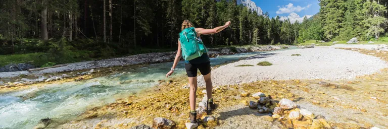 Woman Hiking Through Stream Backpack 768px